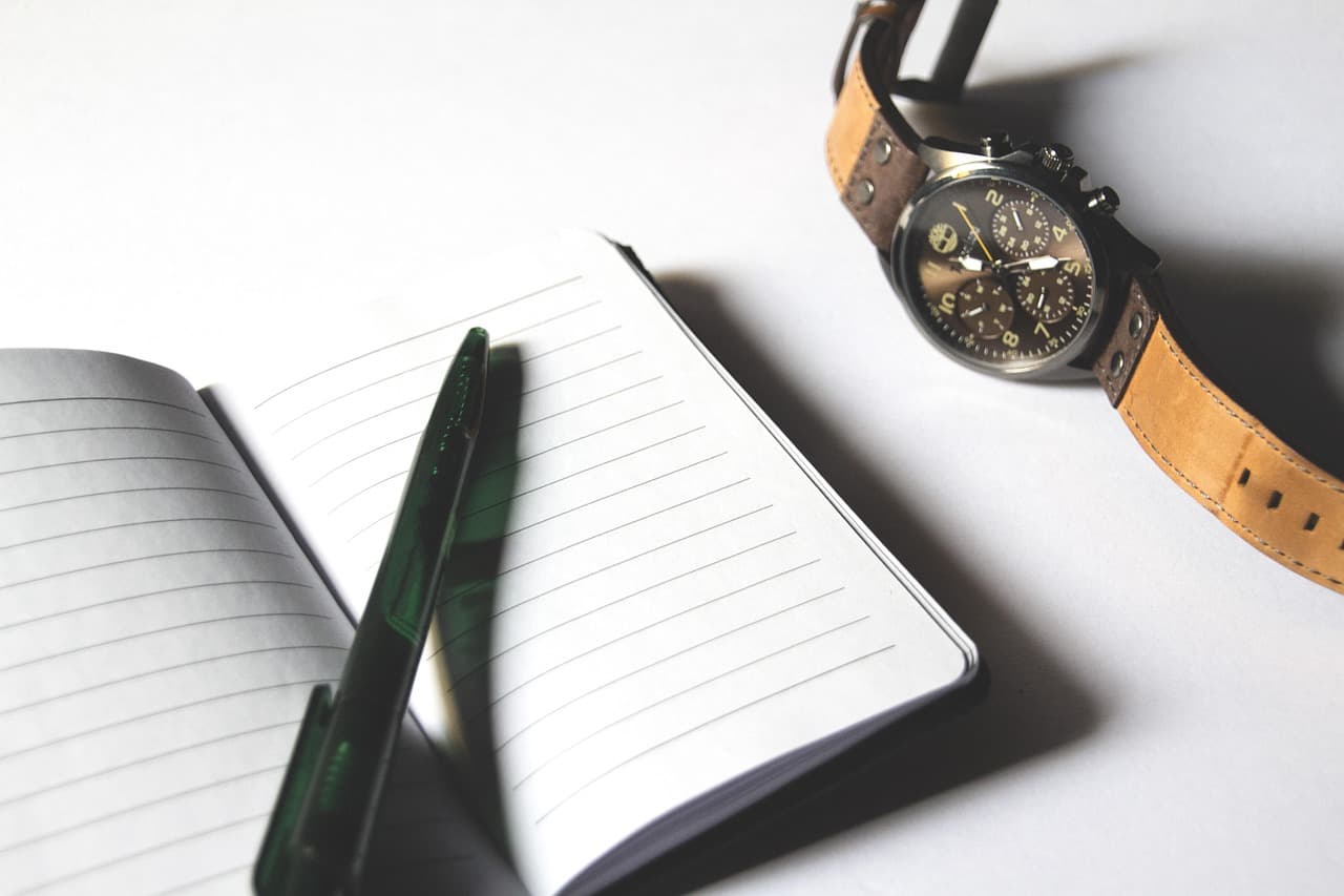 Checklist on paper with a notebook, pen, and watch