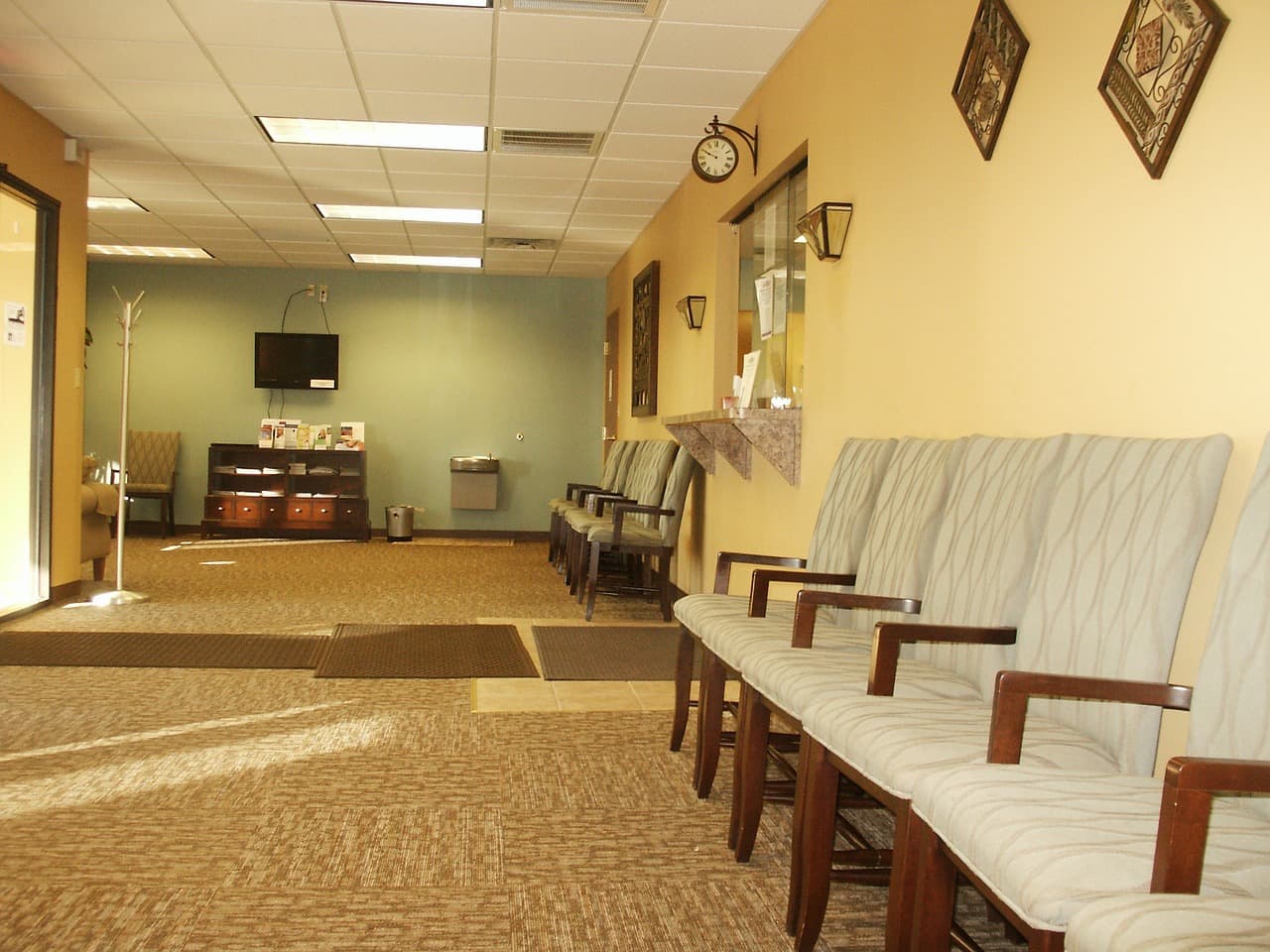Empty medical clinic waiting room with chairs and reception desk