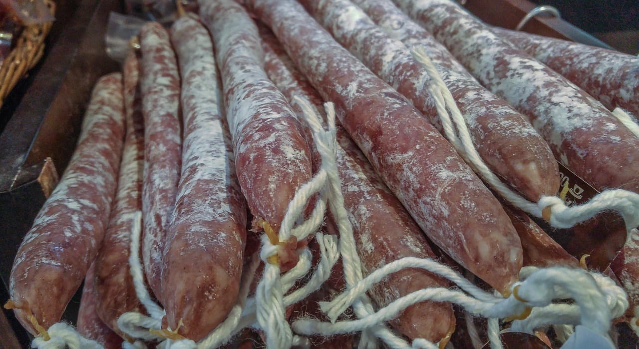 Deli counter display with assorted sausages and cured meats