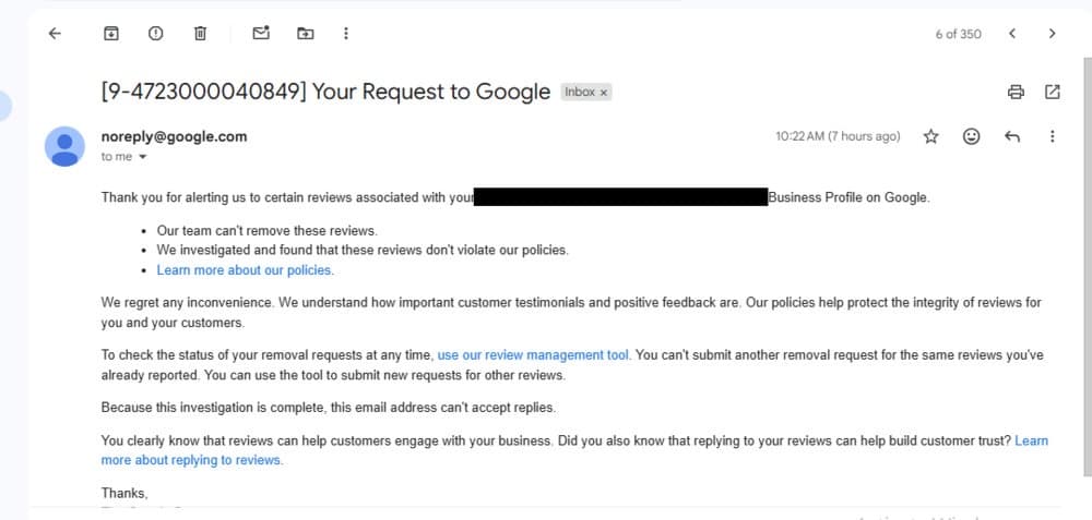Redacted Google response stating a reported review did not violate policy and remained live, business name blacked out